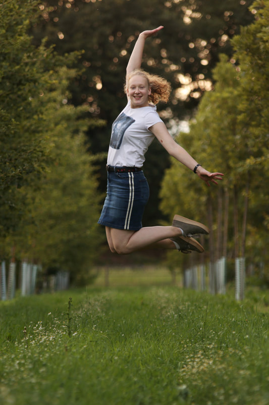 portret springend meisje bomen 